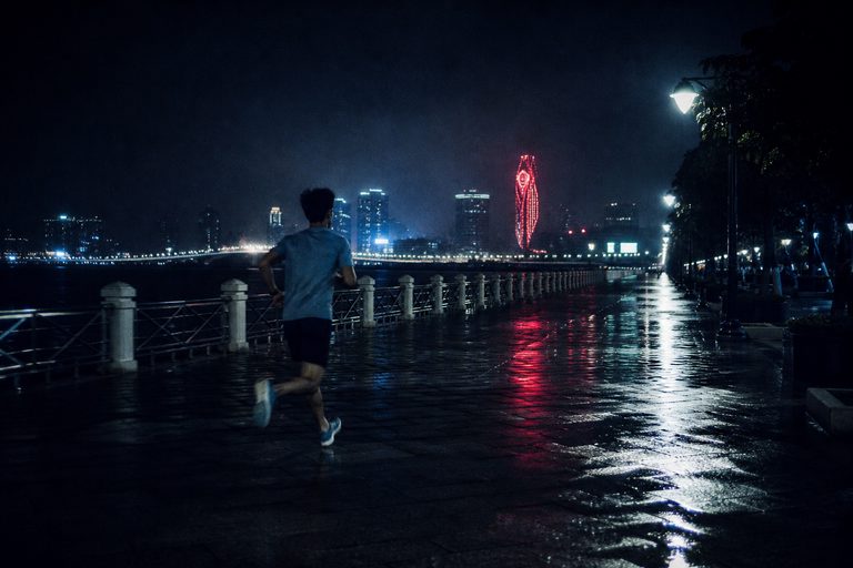 夜晚的澳門海濱，一位跑者沿著長廊前進